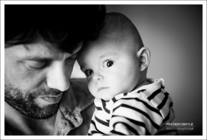 bébé dans les bras de papa fixant le photographe