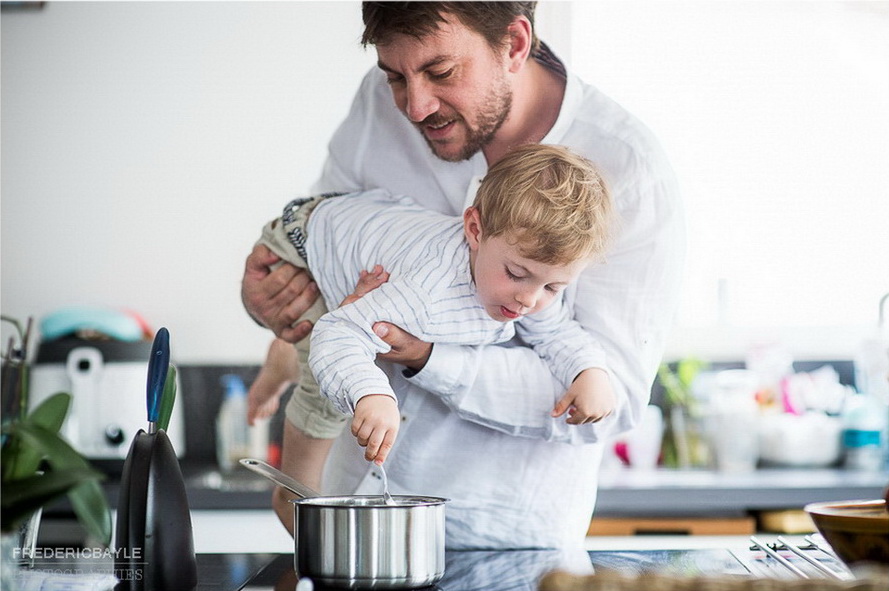 papa faisant la cuisine avec bébé durant un reportage famille