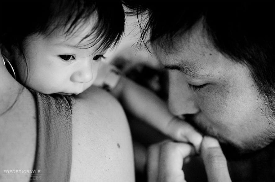 un papa qui embrasse la main de son petit bébé